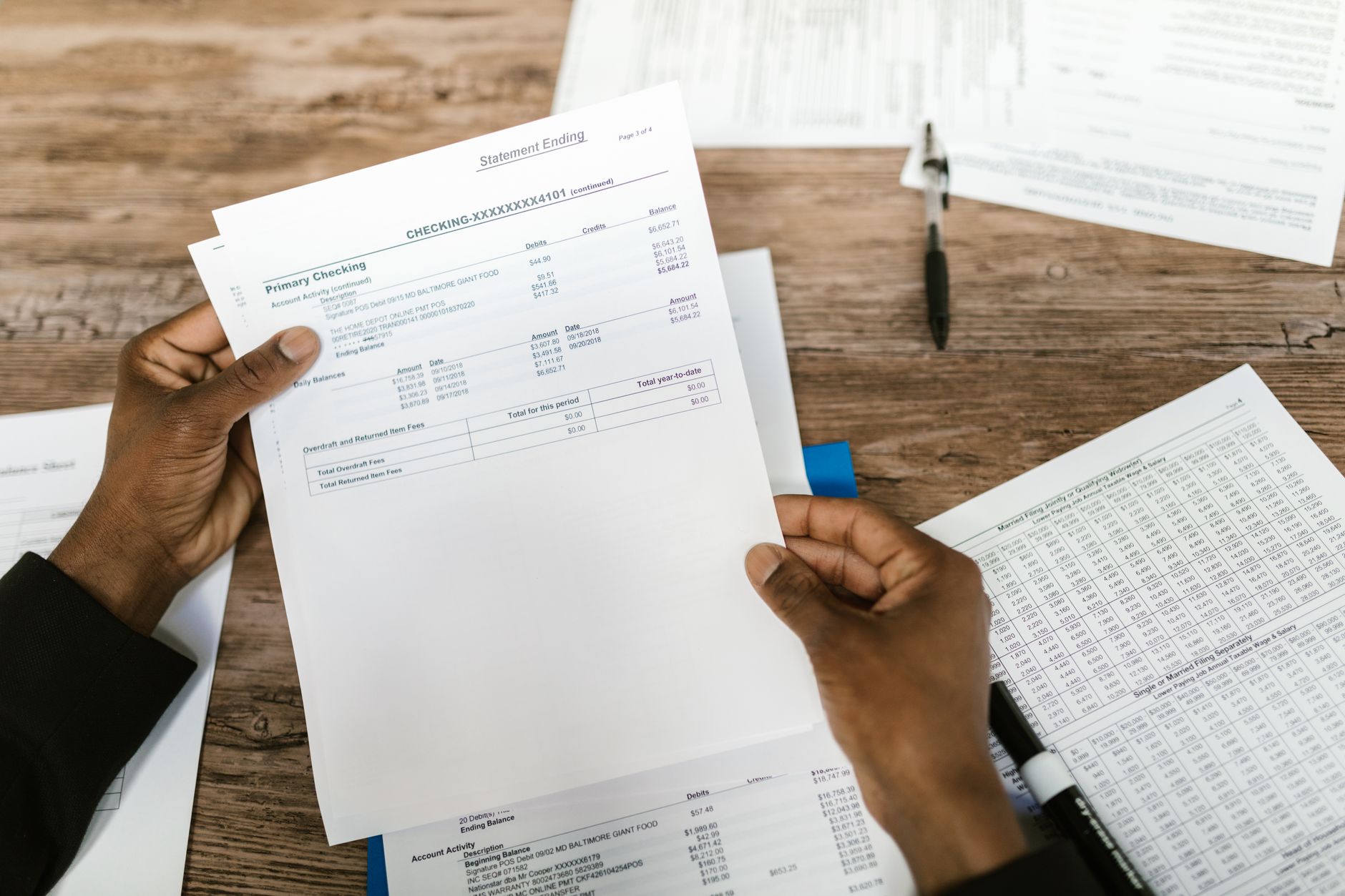 Hands holding a bank statement and financial papers — proof of address and source of funds among KYC documents